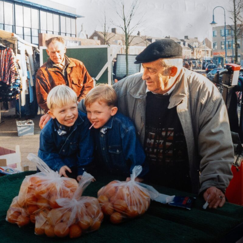 Beverwijkse ondernemer Jacques Davidson, afgebeeld met zijn 2 kleinzoons bij de fruitkraam op de markt.